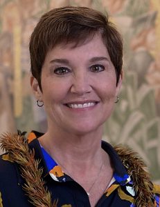 A headshot of a woman with short dark hair. She appears to be outside and is smiling directly at the camera. 